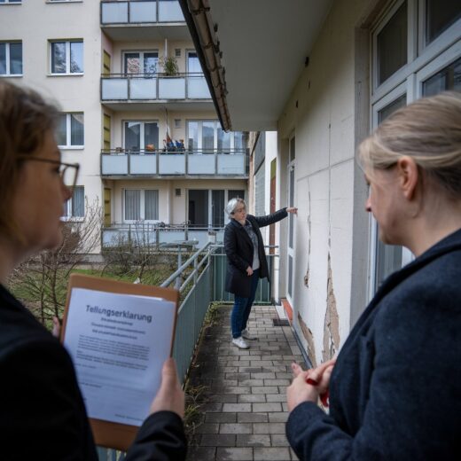 Wohnungseigentümerin zeigt Feuchtigkeitsschäden an der Wand ihrer Terrasse in einem Hamburger Wohnhaus.